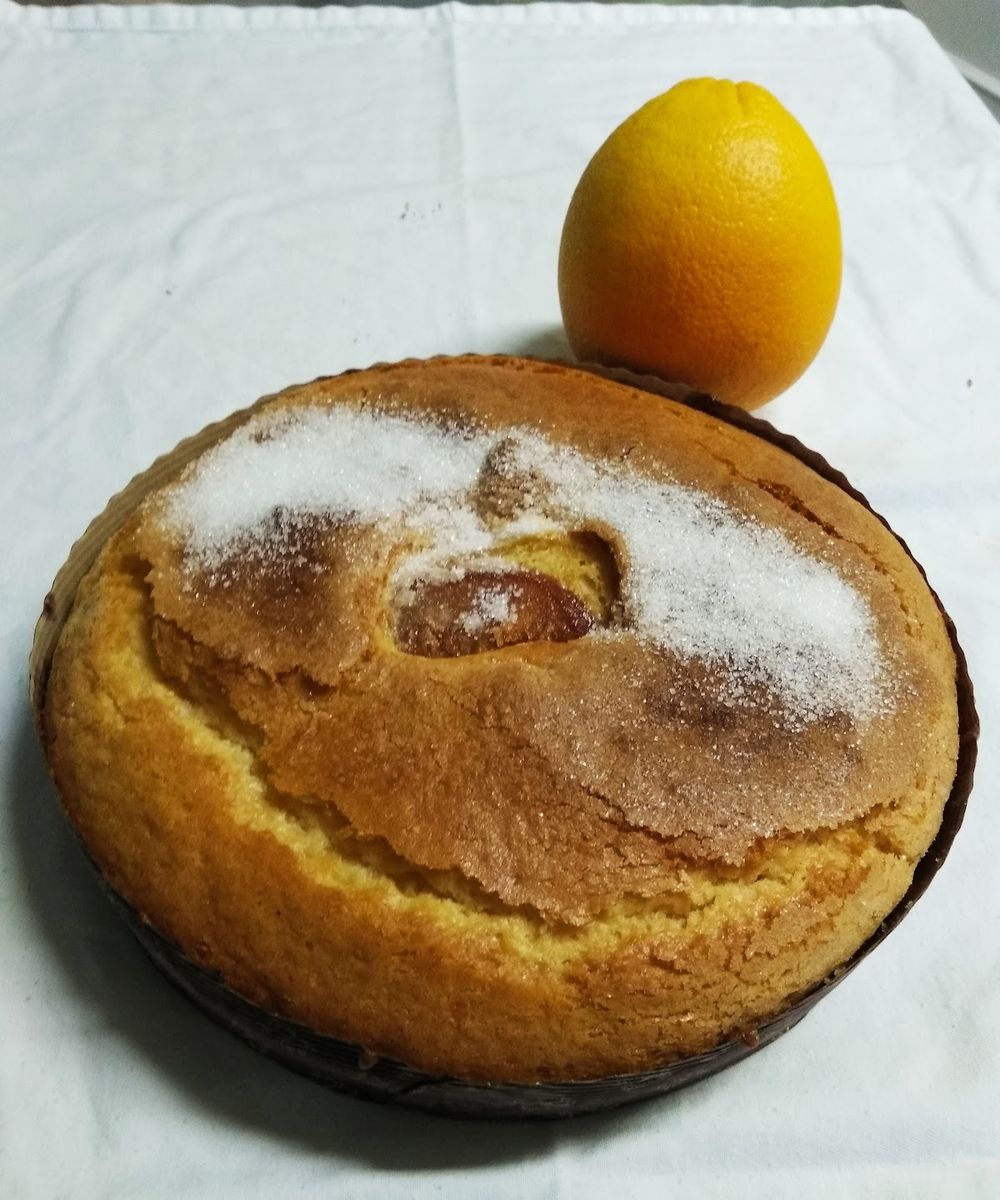 Bizcocho casero espolvoreado con azúcar junto a una naranja