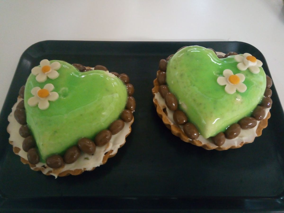 Dos pasteles en forma de corazón verde con flores de azúcar