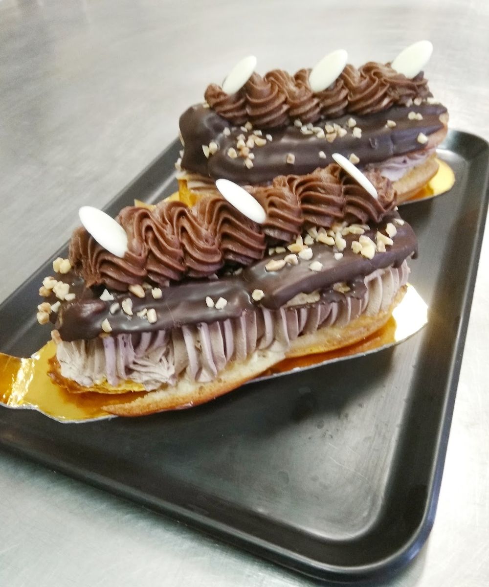 Dos palos de chocolate rellenos de crema y decorados con almendra picada
