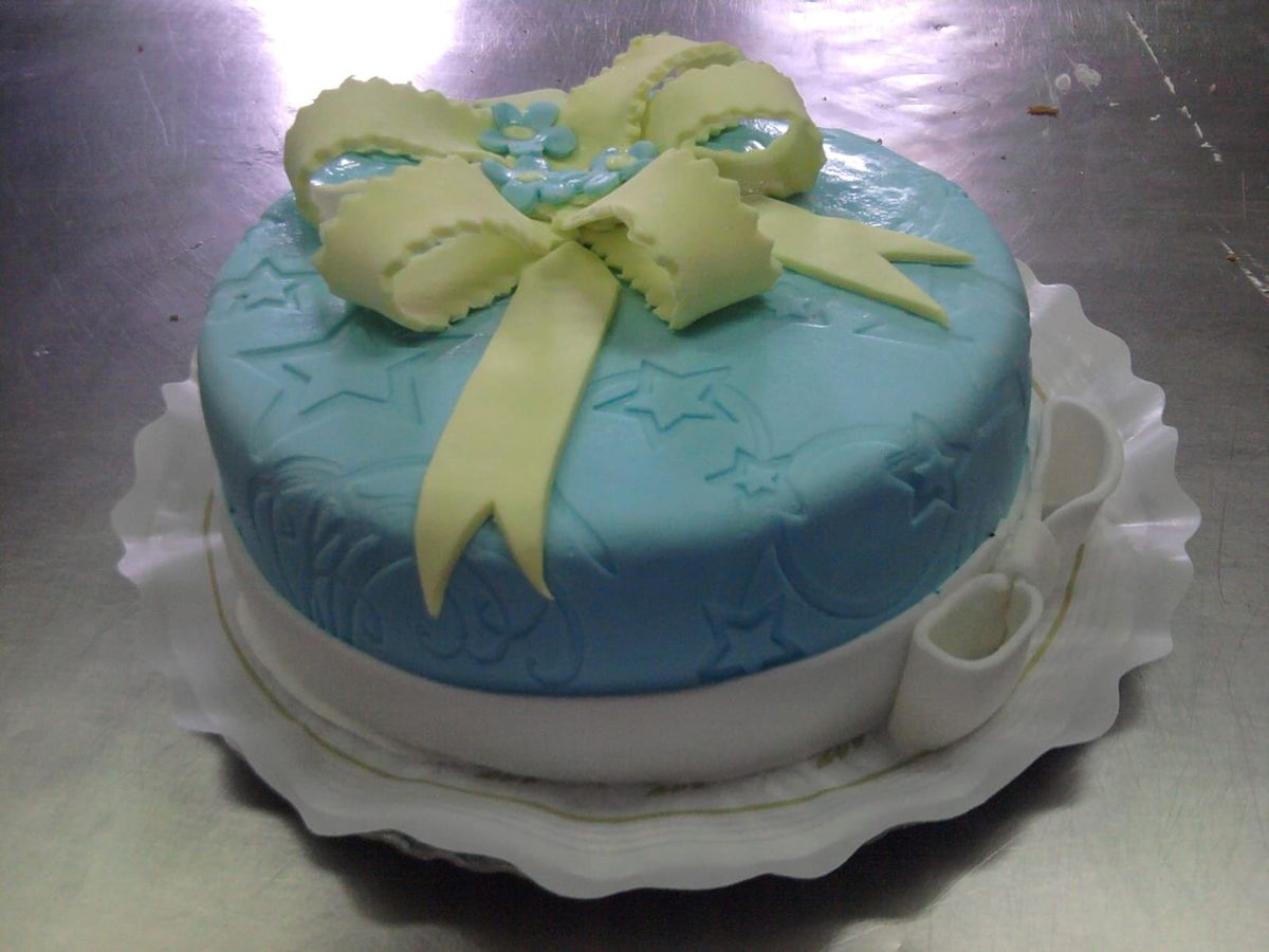 Tarta de fondant azul con forma de regalo y un gran lazo amarillo